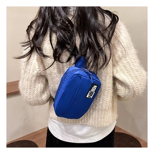 Model wearing bright blue nylon crossbody bag with black 'FASHION' patch detail