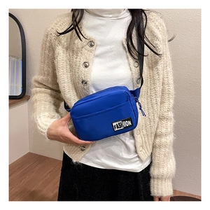 Close-up of blue nylon crossbody bag with fashion label shown on a model