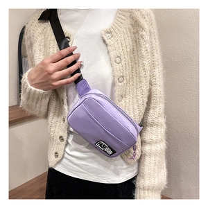 Detail of purple nylon crossbody bag with adjustable strap and fashion label on the front