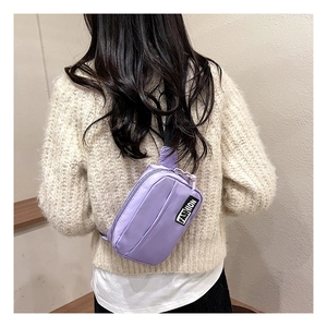 Detail view of purple nylon crossbody chest bag with FASHION patch on female model