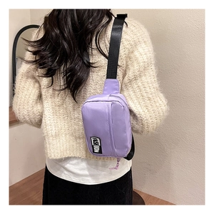 Detail of a purple nylon crossbody bag worn on person showing the black strap and logo