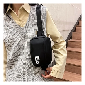 Detail of black nylon crossbody bag with fashion patch and adjustable strap worn by model