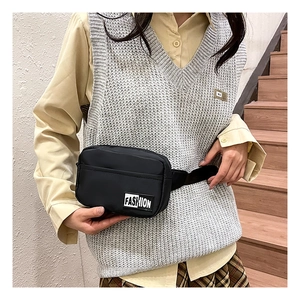 Close-up of black nylon crossbody bag featuring a white Fashion label and zipper detail