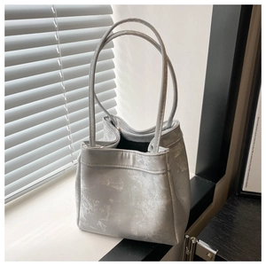 Close-up of a silver-gray bucket bag showing a matte metallic texture and long handles
