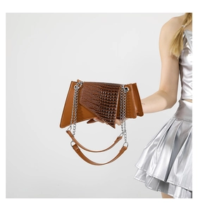 Détail d'un sac bandoulière en cuir marron avec texture crocodile et chaîne argentée
