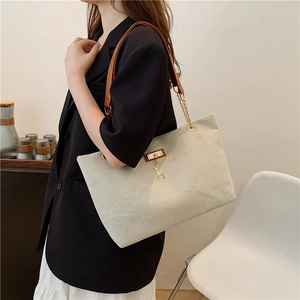 Vintage canvas tote bag with brown leather straps and gold deer charm in a home setting
