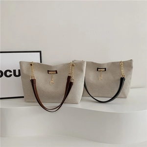 Minimalist canvas tote bags with leather straps and golden deer charms in a white studio