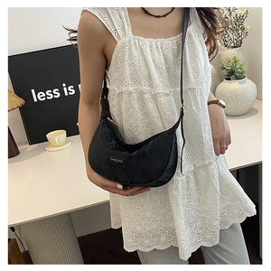 Gros plan d'un sac demi-lune noir en nylon avec logo fashion porté par un mannequin
