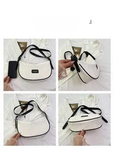 Détail macro du sac selle blanc avec bordures noires contrastées et bandoulière réglable