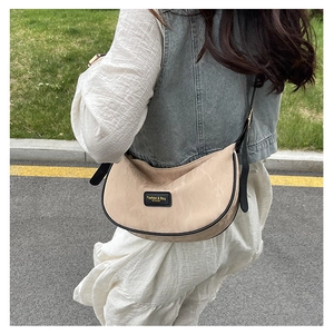 Détail du sac demi-lune beige avec bordure noire et bandoulière réglable pour un style chic