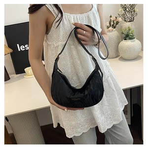 Sac à bandoulière noir plissé en forme de croissant avec sangle réglable porté par un modèle