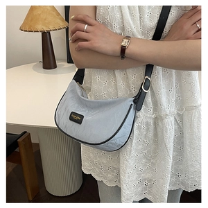 Vue détaillée du sac demi-lune bleu clair avec bandoulière noire et surface texturée