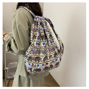 Side view of a canvas drawstring backpack featuring colorful ethnic elephant patterns