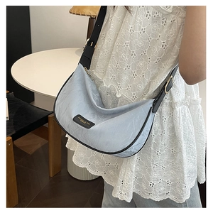 Vue détaillée du sac demi-lune bleu clair avec tissu froissé et finitions en cuir noir