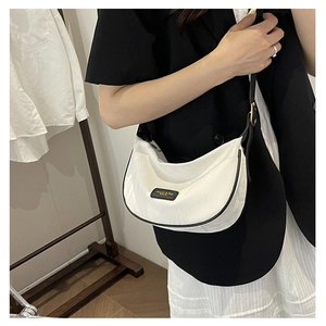 Gros plan d'un sac demi-lune blanc minimaliste avec bordure noire et détails dorés chic