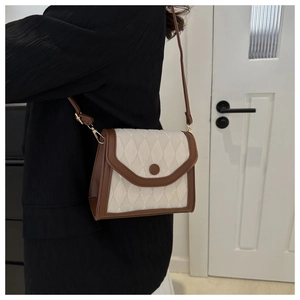 Detail of vintage beige quilted crossbody bag with brown trim and round buckle decoration