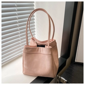 Detail of soft pale pink suede bucket bag with slim shoulder straps in natural sunlight
