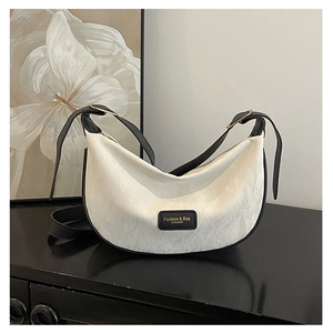 Détail du tissu jacquard et de la garniture en cuir noir sur un sac demi-lune chic
