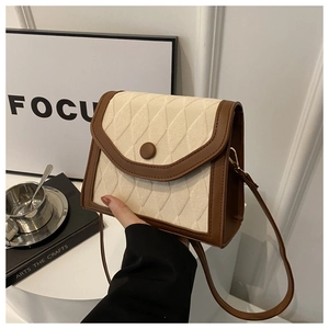 Detail of vintage cream quilted crossbody bag with brown leather trim and button