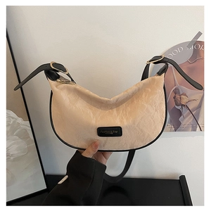 Détail du sac croissant plissé beige avec bordure en cuir noir et boucles dorées