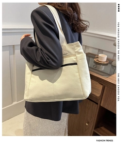 Detail of a cream canvas tote bag with side pockets and sturdy shoulder straps