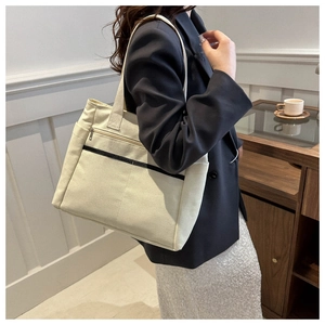 Detail of minimalist cream canvas tote bag with black decorative lines and metal zipper pocket