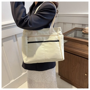 Close-up of minimalist cream canvas tote bag with functional pockets and wide straps
