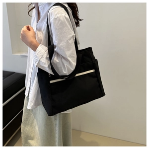 Detail view of large canvas tote bag showing side pocket and white decorative stripe