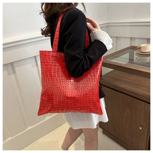 Macro detail of red tote bag featuring gold crocodile skin texture and sturdy straps