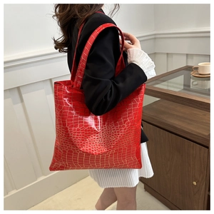 Side view of a bright red crocodile pattern tote bag being worn over the shoulder