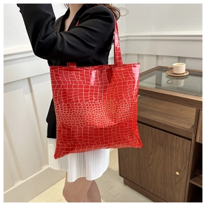 Detail showing the glossy red crocodile embossed pattern on a large capacity tote bag