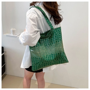 Detail view of the green crocodile pattern texture on a large capacity tote shoulder bag