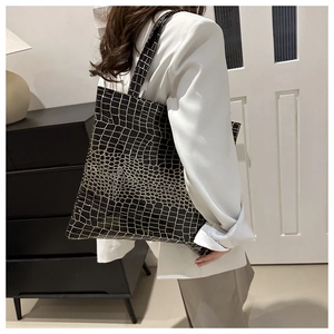 Detail showing large black tote bag with gold crocodile texture on model's shoulder