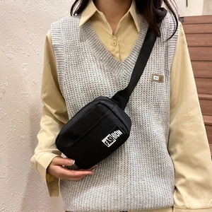 Minimalist black nylon crossbody bag with adjustable strap worn by model in casual setting