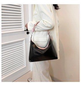 Detail of black faux leather tote with pink trim and adjustable metal strap buckle