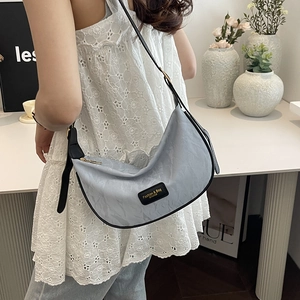 Sac croissant bleu clair à motif marbré avec bandoulière noire porté par mannequin