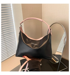 Detail of a black Hobo tote with pink strap and 'FASHION' text in natural window light