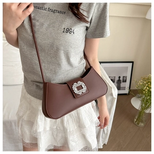 Close-up of brown faux leather underarm bag with sparkling rhinestone buckle detail