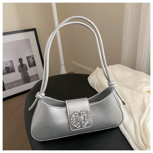 Detail of silver metallic shoulder bag featuring a crystal buckle and dual knotted straps