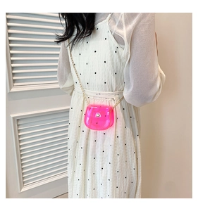 Détail du mini sac bandoulière rose néon avec chaîne dorée sur robe blanche
