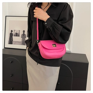 Détail du sac besace rose avec boucle dorée carrée et texture en cuir mat élégant