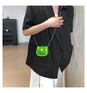Détail du mini sac transparent vert fluo avec une élégante bandoulière en chaîne dorée