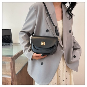 Chic sac besace en cuir noir avec boucle dorée porté par un mannequin dans un bureau
