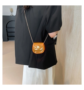 Gros plan sur le mini sac en PVC orange transparent avec fine bandoulière chaîne dorée