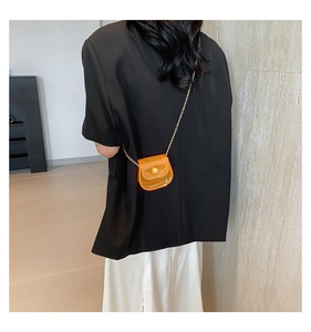 Détail du mini sac bandoulière orange translucide en PVC avec chaîne et boucle dorées