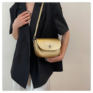 Détail du sac besace doré champagne métallisé avec boucle carrée sur costume noir