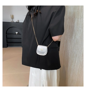 Vue détaillée du mini sac selle avec chaîne dorée sur une tenue de blazer noir