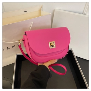Détail du sac de selle rose vif avec fermoir doré géométrique et texture en cuir fin