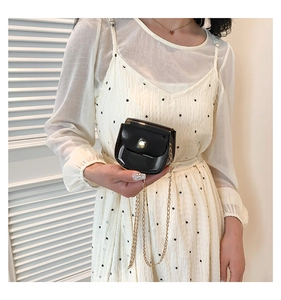 Vue détaillée d'un mini sac chaîne en cuir verni noir avec boucle en perle
