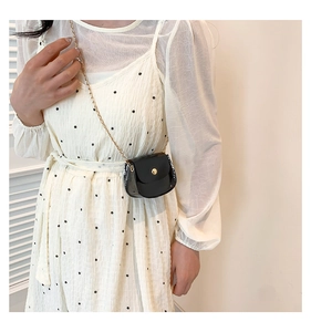Détail d'un mini sac bandoulière en cuir verni noir avec une bandoulière chaîne dorée